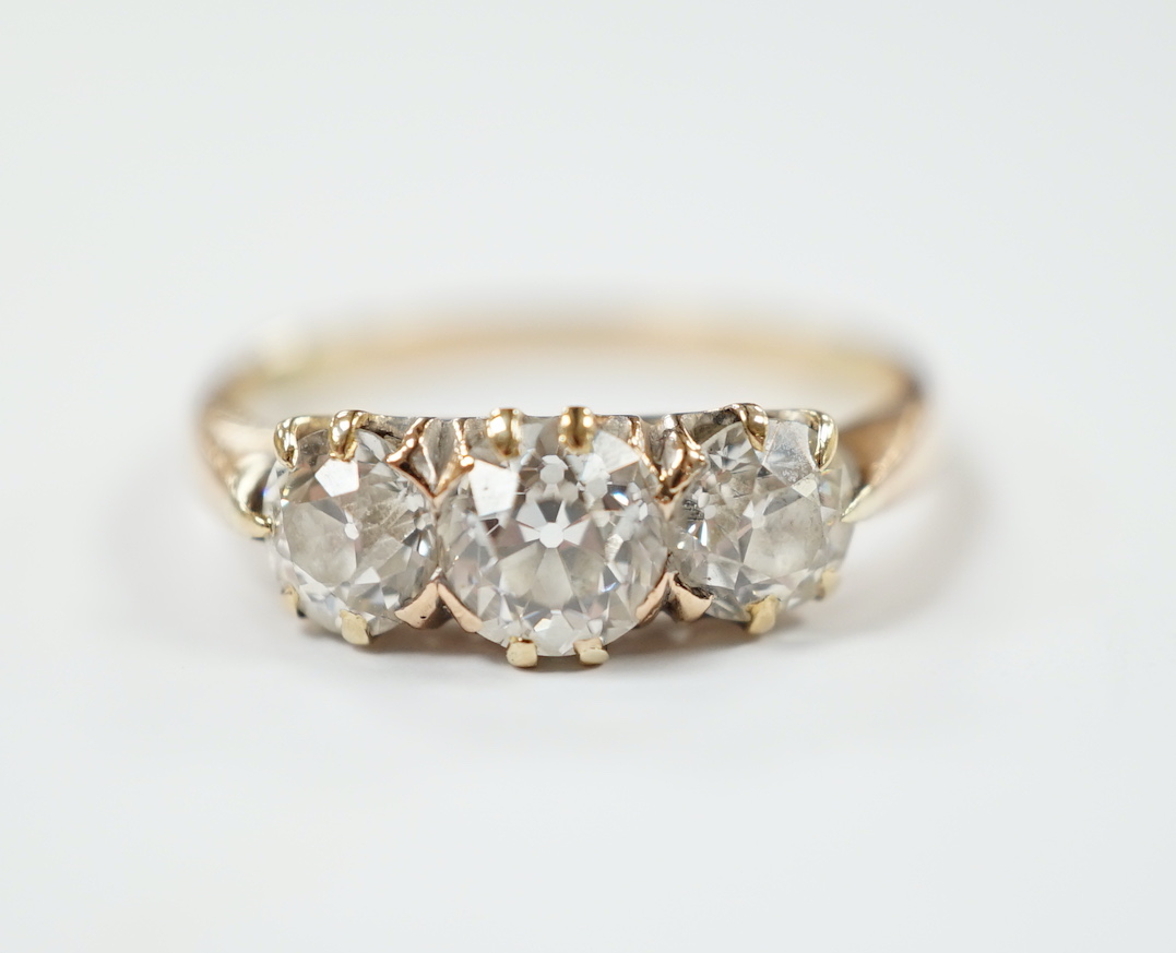 A yellow metal and three stone diamond set ring, size P, gross weight 2.6 grams.
